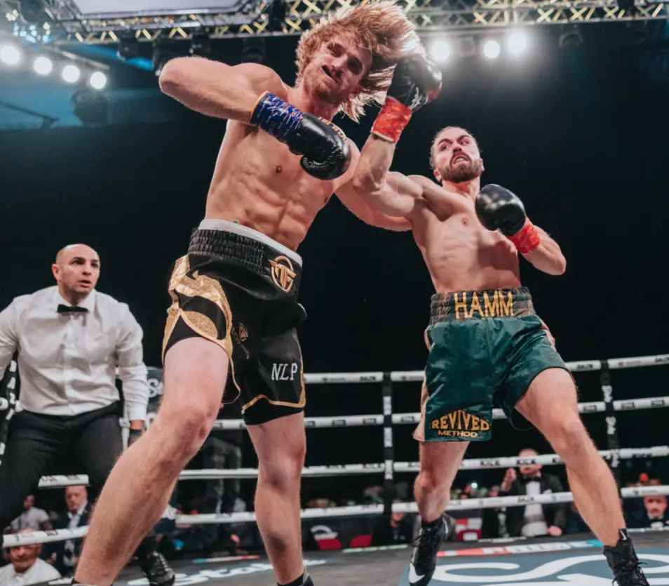 Two boxers exchanging punches in a ring, with Tristan Hamm throwing a devastating punch; referee observing in the background.